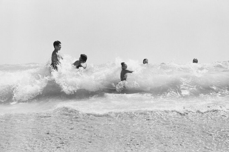 Photograph of kids playing in waves at beach