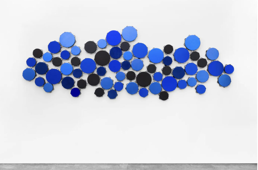 Installation of several blue tambourines on a wall